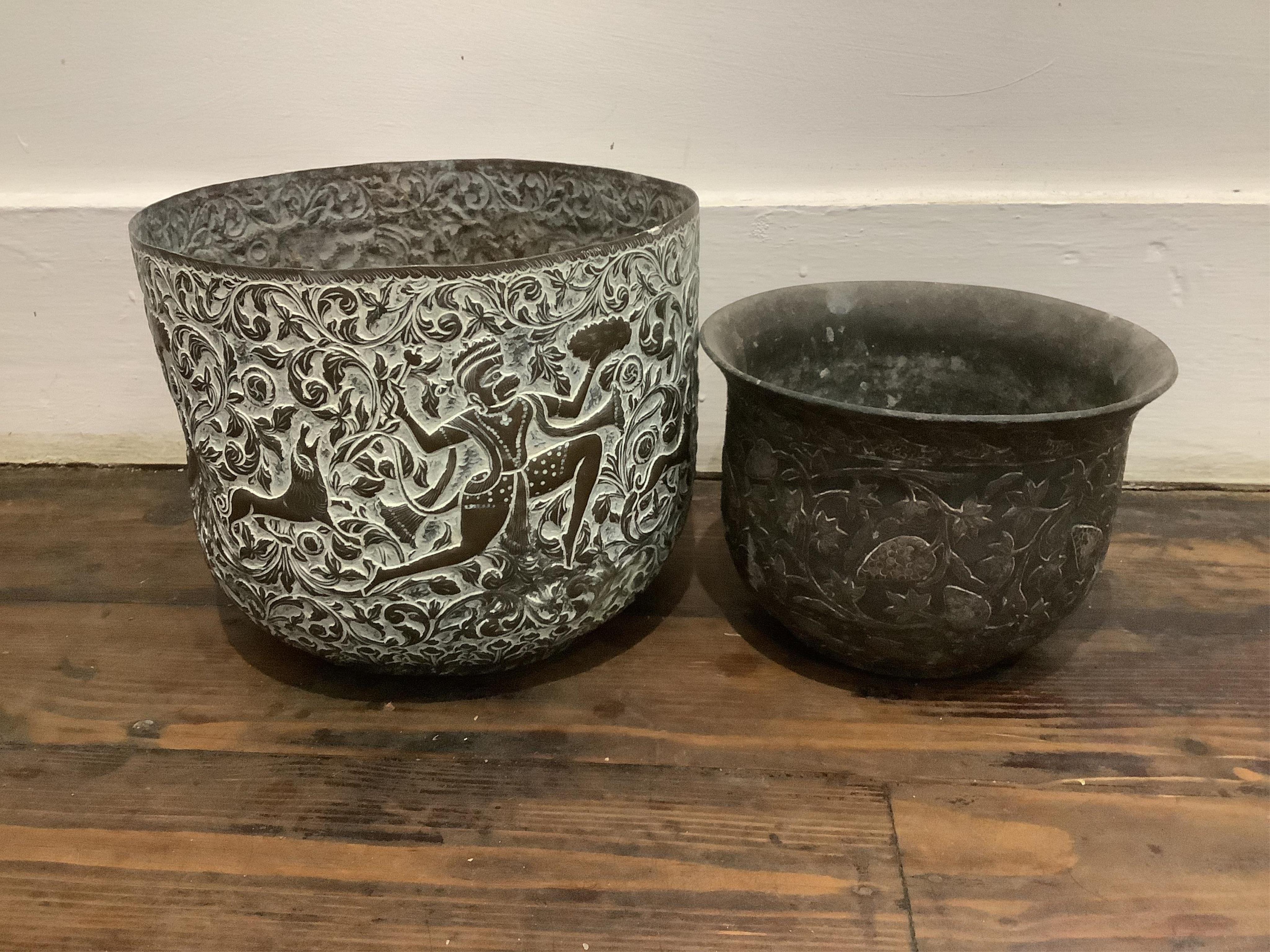 An Indian bidriware jardiniere decorated with fruiting plants and fish, 12.5cm and an embossed brass jardiniere decorated with monkey gods, 17.5cm.